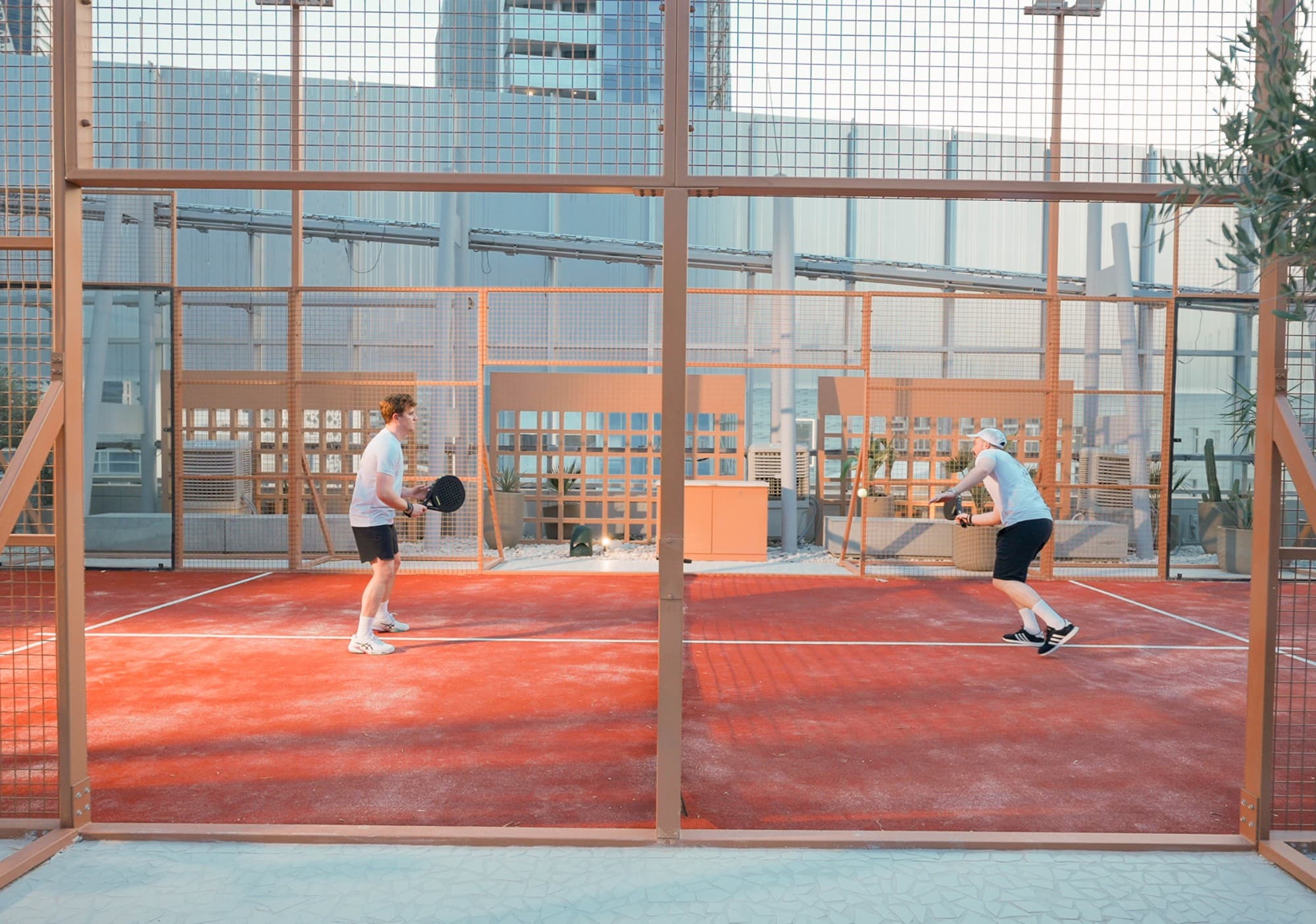 Outdoor padel court at KAFD 2.08 in Riyadh, featuring bright blue surfaces and surrounding greenery